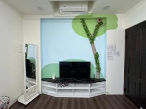 a room with a tv and a palm tree on the wall at Yixiangjing Guesthouse in Zhushan