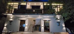 a white house with a staircase and a balcony at Desert Oasis Camp And Resort in ladakh +7 photos