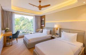 a hotel room with two beds and a window at Goldfinch Panjim Goa in Old Goa +9 photos