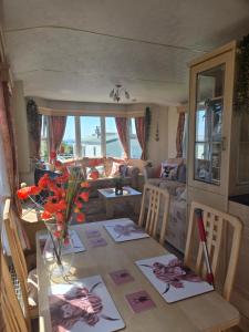 a dining room table with a vase of flowers on it at Serenity in Monreith +19 photos