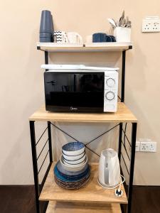 a microwave on a shelf with plates and dishes at Casa Le Rock in Kuah