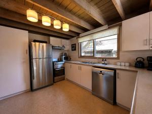 a kitchen with a stainless steel refrigerator and a window at Brindabella Chalet alpine-getaways in Dinner Plain