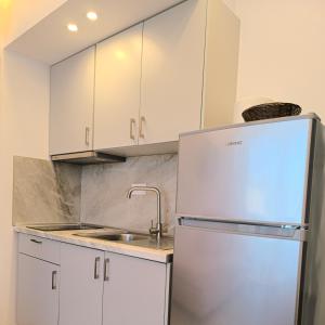 a kitchen with white cabinets and a stainless steel refrigerator at Calm Luxury Villas in Limenaria