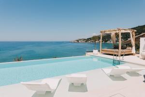 a swimming pool with white chairs and the ocean at KAAB Boutique Hotel in Ulcinj