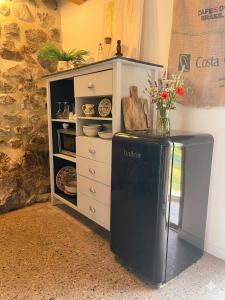 a black refrigerator in a kitchen with a dresser at Petite maison ardéchoise in Saint-Michel-de-Chabrillanoux