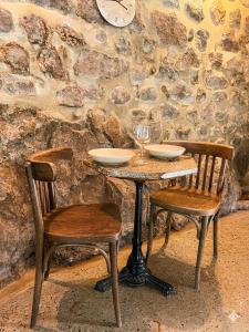 a table with two chairs and a clock on a wall at Petite maison ardéchoise in Saint-Michel-de-Chabrillanoux