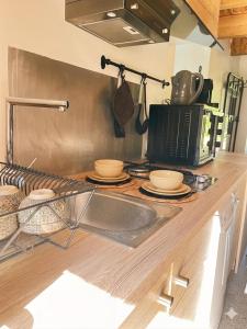a kitchen counter with a sink and a microwave at Petite maison ardéchoise in Saint-Michel-de-Chabrillanoux