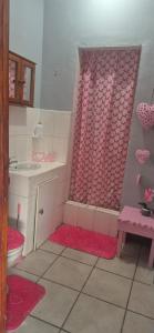 a pink bathroom with a sink and a toilet at Over the Rainbow Guest House in Hibberdene
