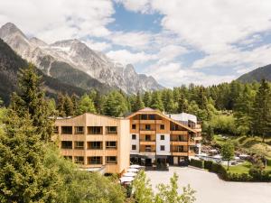 a hotel with mountains in the background at Falkensteiner Hotel Antholz l Adults Only in Anterselva di Mezzo
