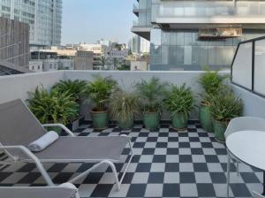 a balcony with a checkered floor and chairs and plants at Theodor Rothschild Tel-Aviv in Tel Aviv +22 photos