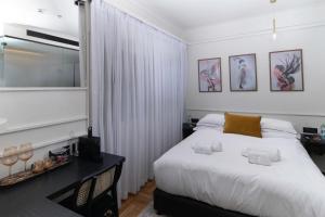 a bedroom with a large white bed and a desk at Theodor Rothschild Tel-Aviv in Tel Aviv