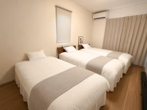 a row of three beds in a hotel room at OTE HOUSE shime in Shime