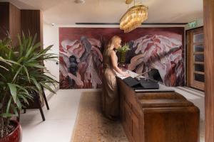 a woman standing in a room with a painting at Theodor Rothschild Tel-Aviv in Tel Aviv