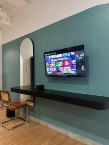 a tv on a wall with a table and a chair at And Living Hotel in Kejayan