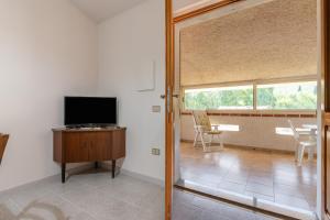 a living room with a flat screen tv and a table and chairs at Casa Vacanza Iris in Perdaxius