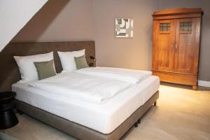 a bedroom with a large bed with white sheets at Landgut Stemmen in Stemmen