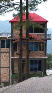 ein großes Holzhaus mit rotem Dach in der Unterkunft Down Town in Nathia Gali