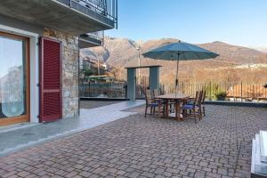 a table and chairs with an umbrella on a patio at Studio Apartment Lake and Relax in Gravedona
