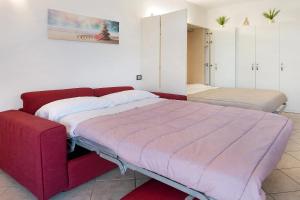 a bedroom with two beds and a red couch at Studio Apartment Lake and Relax in Gravedona