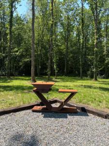 a picnic table and a bench in a park at Le refuge du KL in Bomal