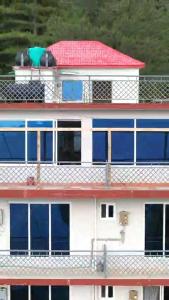 ein Gebäude mit blauen Fenstern und einem roten Dach in der Unterkunft Down Town in Nathia Gali + 21 Fotos