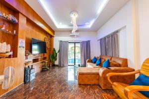 a living room with a couch and a tv at Richpoolvilla Pattaya in Jomtien Beach