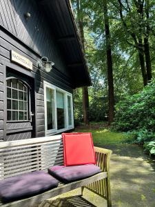 a red chair sitting on a bench in front of a house at Kleine huisje op de Veluwe in Otterlo