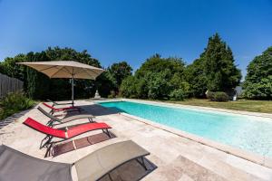 a swimming pool with chairs and an umbrella next to it at Chambres d'hôtes Château Cajus in Saint-Germain-du-Puch