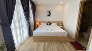 a bedroom with a bed and a large window at Zanya villa & coffee in Da Lat