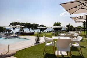 un gruppo di tavoli e sedie con ombrelloni accanto a una piscina di Vision Hotel a Peschiera del Garda Altre 33 foto