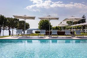 un gruppo di sedie e ombrelloni accanto a una piscina di Vision Hotel a Peschiera del Garda