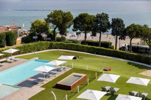 una piscina con ombrelloni bianchi e una spiaggia di Vision Hotel a Peschiera del Garda