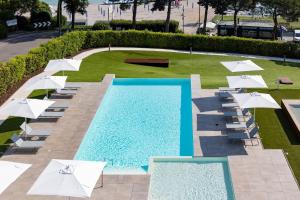 una piscina con ombrelloni e sedie bianche accanto a un resort di Vision Hotel a Peschiera del Garda