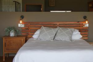 a bedroom with a white bed with a wooden headboard at Stroomrivier Lodge in Boshoek