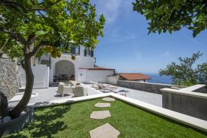 a garden with a tree and chairs and the ocean at Villa CristAl in Praiano