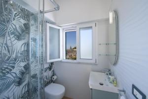 a bathroom with a toilet and a sink and two windows at Villa CristAl in Praiano +35 photos