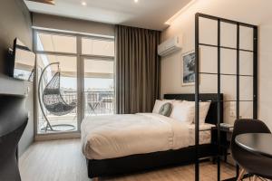 a bedroom with a bed and a desk and a balcony at Au Piree by Calon in Piraeus