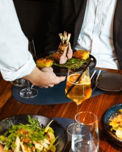 a person holding a plate of food on a table at ARCOTEL Wimberger Wien in Vienna