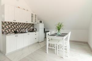 a kitchen with white cabinets and a table and chairs at Apartament Nowinka in Tatary