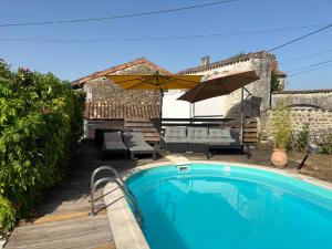 a swimming pool in front of a house with an umbrella at Le Phœnix in Linars
