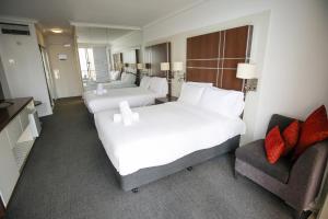 a hotel room with two beds and a chair at Beachside Studio with Stunning Ocean View in Gold Coast