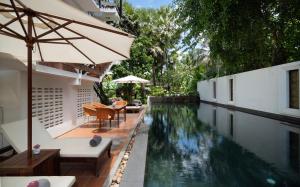 an outdoor swimming pool with an umbrella next to a house at The Urban in Siem Reap
