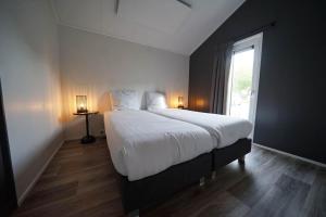 a bedroom with a large white bed and a window at EuroParcs Kaatsheuvel in Kaatsheuvel