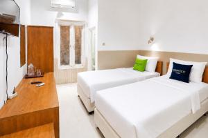a bedroom with two beds and a television at Urbanview Hotel RDN Oasis Cisarua by RedDoorz in Brujul