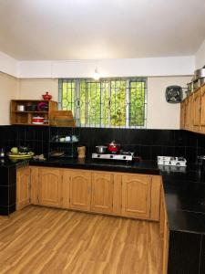 a kitchen with black counter tops and wooden cabinets at Ananda Homestay in Tawang