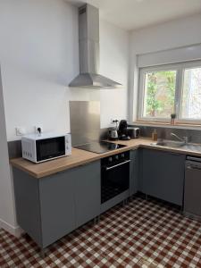 a kitchen with a microwave oven and a sink at Maison des Capucins in Nérac