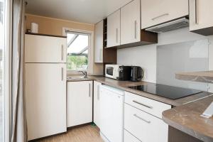 a kitchen with white cabinets and a microwave at Diófa Vendégház in Pilismarót