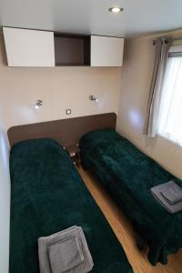 two beds in a small room with green sheets at Diófa Vendégház in Pilismarót +5 photos