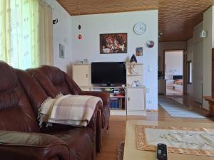 a living room with a brown leather couch and a tv at Suns Tupa - Travellers Marmalade in Siikalatva
