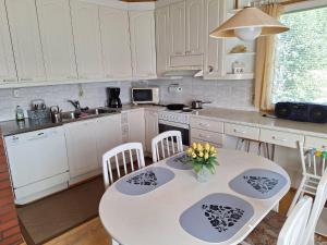a kitchen with a table with chairs and a sink at Suns Tupa - Travellers Marmalade in Siikalatva